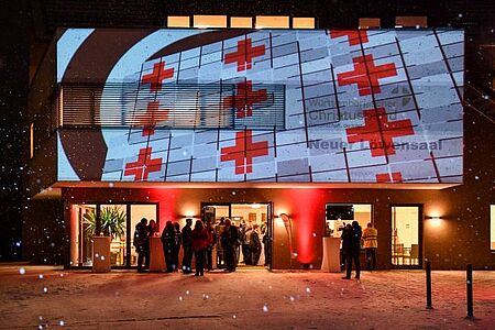 zu sehen ist eine Lichtpräsentation eines DRK-Logos auf die Eingangswand des Löwensaals Weilheim